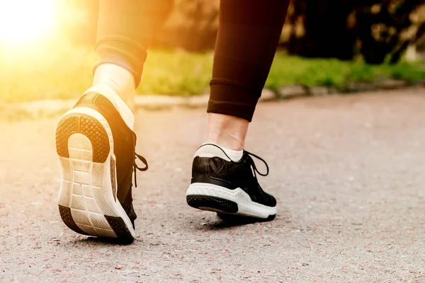 Morning running. Young lady running on a rural road during sunset in black sneakers with white sole