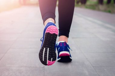 Sabah koşusu. Kırsal bir yolda koşan genç bayan gün batımında siyah tabanlı mavi spor ayakkabılarla koşuyor. Sağlıklı bir yaşam tarzı. Spor eğitimi konsepti