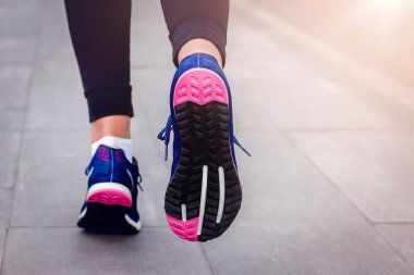 Sabah koşusu. Kırsal bir yolda koşan genç bayan gün batımında siyah tabanlı mavi spor ayakkabılarla koşuyor. Sağlıklı bir yaşam tarzı. Spor eğitimi konsepti