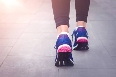 Sabah koşusu. Kırsal bir yolda koşan genç bayan gün batımında siyah tabanlı mavi spor ayakkabılarla koşuyor. Sağlıklı bir yaşam tarzı. Spor eğitimi konsepti