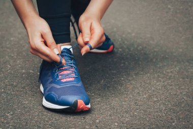 Akşam koşusu. Kırsal bir yolda mavi spor ayakkabılarla günbatımında koşan genç bir bayan. Koşmadan önce ayakkabı bağcıklarını bağlayan kız