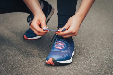 Akşam koşusu. Kırsal bir yolda mavi spor ayakkabılarla günbatımında koşan genç bir bayan. Koşmadan önce ayakkabı bağcıklarını bağlayan kız