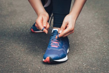 Akşam koşusu. Kırsal bir yolda mavi spor ayakkabılarla günbatımında koşan genç bir bayan. Koşmadan önce ayakkabı bağcıklarını bağlayan kız