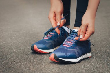 Akşam koşusu. Kırsal bir yolda mavi spor ayakkabılarla günbatımında koşan genç bir bayan. Koşmadan önce ayakkabı bağcıklarını bağlayan kız