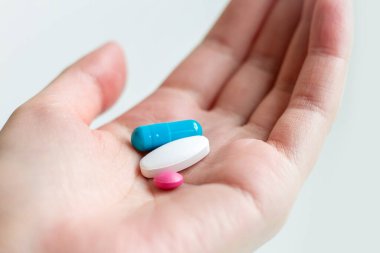 Beyaz arka planda kadın avucunda mavi ve beyaz hap kapsülü var. Kadın elinde antidepresan haplar. Avucunun içinde hap tutan bir kadın.