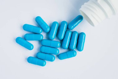 Mavi kapsüller, açık mavi arka planda haplar. Kapsüller beyaz teneke kutuda. Vitaminler, kadın sağlığı için besin takviyeleri