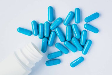Mavi kapsüller, açık mavi arka planda haplar. Kapsüller beyaz teneke kutuda. Vitaminler, kadın sağlığı için besin takviyeleri