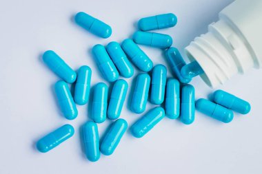 Mavi kapsüller, açık mavi arka planda haplar. Kapsüller beyaz teneke kutuda. Vitaminler, kadın sağlığı için besin takviyeleri