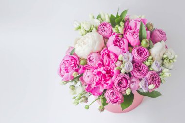 Şapka kutusunda çiçek aranjmanı. Şakayık buketi, Eustoma, pembe bir kutuya gül serpmek, arka planda beyaz bir vaha ve fotokopi alanı.