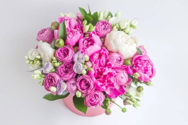 Şapka kutusunda çiçek aranjmanı. Şakayık buketi, coşku, pembe bir kutuda gül, beyaz bir arka planda vaha.