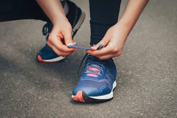 Akşam koşusu. Kırsal bir yolda mavi spor ayakkabılarla günbatımında koşan genç bir bayan. Koşmadan önce ayakkabı bağcıklarını bağlayan kız