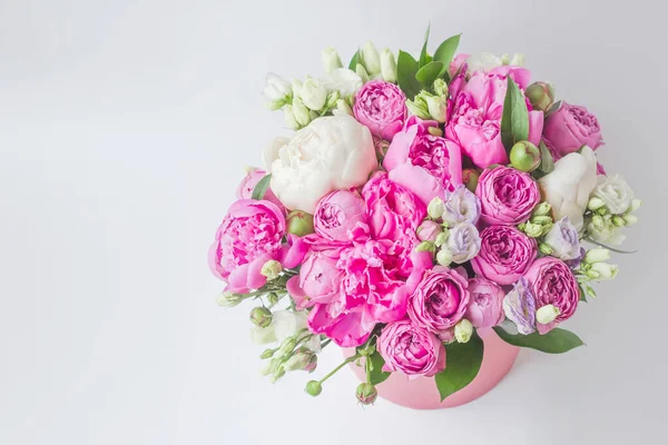 Şapka kutusunda çiçek aranjmanı. Şakayık buketi, Eustoma, pembe bir kutuya gül serpmek, arka planda beyaz bir vaha ve fotokopi alanı.