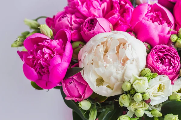 Arrangement of flowers in a hat box. Bouquet of peonies, eustoma, spray rose in a pink box with an oasis on a white background