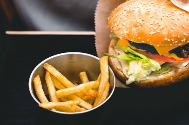Siyah ahşap masada patates kızartmalı taze lezzetli hamburger.