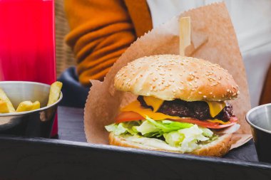 Siyah ahşap masada patates kızartmalı taze lezzetli hamburger.