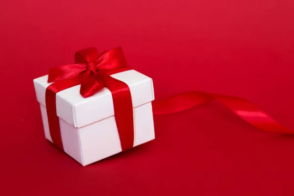 White box with a red ribbon on a red background. Greeting card concept