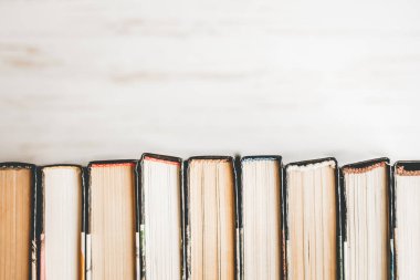 Bir yığın eski kitap, beyaz ahşap arka planda ders kitapları. Hafif arkaplanda satır aralığı