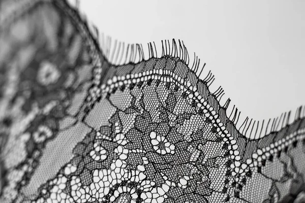 Black lace on gray background. Lace with floral ornaments