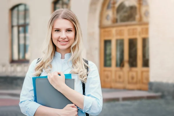 Blond Student Smiler Holder Mappe Notatbok Hendene Universitetsbakgrunn Jente Står – stockfoto