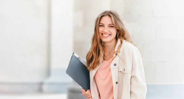 年轻的金发女学生对着大学微笑 可爱的女学生手里拿着文件夹和笔记本 教育概念 网页横幅 复制空间 — 图库照片