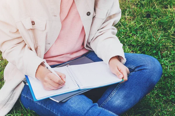 Female hands write in a notebook. The girl writes down her thoughts, a fragment of a notebook and hands