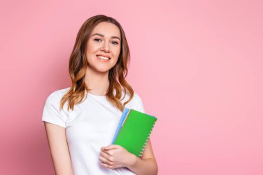 Mutlu öğrenci kız gülümser ve boş fotokopi alanını gösterir, kapat. Pembe arka planda izole edilmiş genç bir kadının portresi.