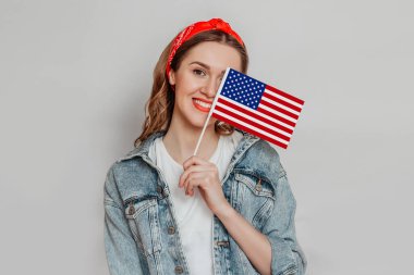 Kırmızı rujlu mutlu genç kız elinde küçük bir Amerikan bayrağı ve gri arka planda izole edilmiş gülümsemeler, elinde ABD bayrağı tutan kız, 4 Temmuz Bağımsızlık Günü, kopyalama alanı