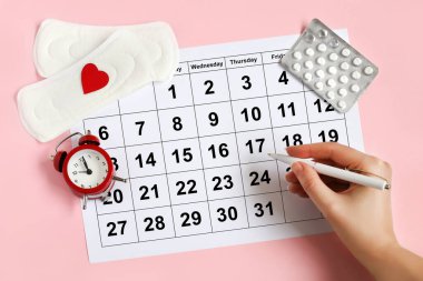 Regl takvimi, çalar saat, hormonal doğum kontrol hapları. Kadınların adet döngüsü konsepti. Regl gecikmesi konsepti