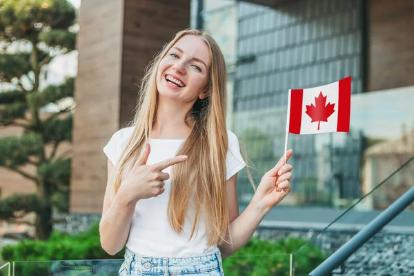年轻的女学生展示了一面小加拿大国旗 站在学校的背景下 — 图库照片
