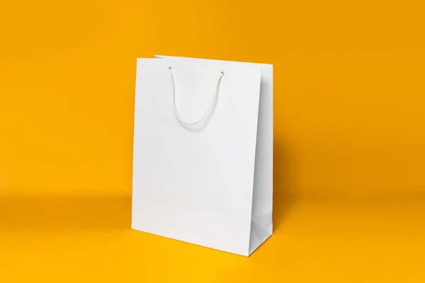 Mockup of white shopping bag isolated over orange paper background. side view