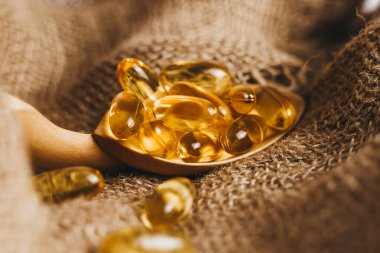 Tahta kaşıkta balık yağı kapsülleri. Balık yağı hapları, çuval bezinde haplar. Vitamin kompleksi Omega 3,6,9. Kapat.