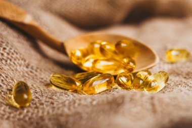 Vitamin kompleksi Omega 3,6,9. Tahta kaşıkta balık yağı kapsülleri. Balık yağı hapları, çuval bezinde haplar. Boşluğu kopyala