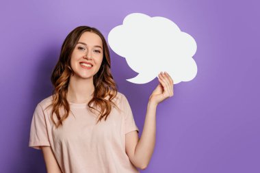 Kafkasyalı genç bir kadının portresi beyaz kağıt konuşma balonu taşıyor. Mor arka planda izole edilmiş tişört giydiğini düşünüyor.