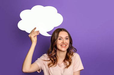 Elinde boş konuşma balonu kağıtları tutan genç bir kadın. Mor arka planda. Leylak üzerine yazı için beyaz kağıt bulutu. Boşluğu kopyala