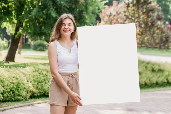 Jovem Estudante Caucasiano Segurando Cartaz Papel Branco Sorrindo Fundo Parque — Fotografia de Stock