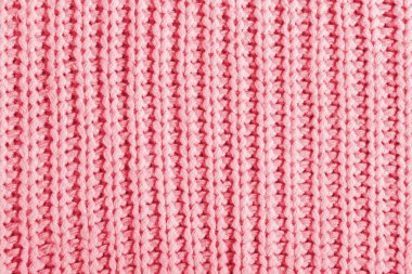 Büyük bir örgü süveterin pembe dokusu. Örülmüş eşarp arka planı, kışlık rahat tekstil arka planı