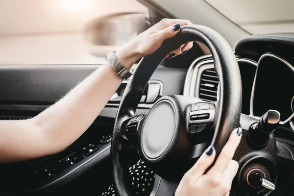 Female hands on the steering wheel of a car. female hand is holding the steering wheel of a car. close up. Traveling alone. Traffic Laws. Learns to drive a car. woman driver