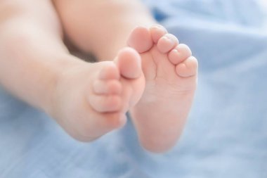 Bebek bacakları mavi bir battaniyenin üzerinde uzanıyor. Bebek sağlığı. Bacak motor becerileri