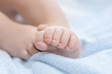 Bebek bacakları mavi bir battaniyenin üzerinde uzanıyor. Bebek sağlığı. Bacak hareketleri. Boşluğu kopyala