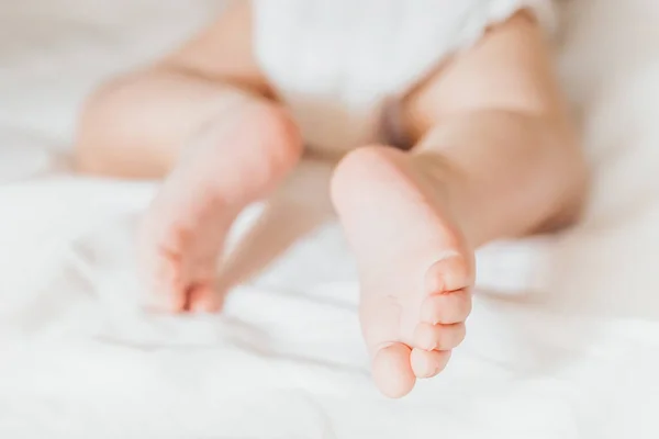 Dziecko Czołga Się Białym Łóżku Nogi Noworodka Wyglądają Prosto Opieka — Zdjęcie stockowe