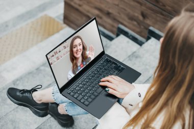 Video aramaları konsepti. Genç bir Ukraynalı kadın monitör ekranından elini sallıyor. Çevrimiçi giyin. Mesafe öğrenme. Laptop ekranında bir kadının portresi video konferansı aracılığıyla başka bir kadınla konuşuyor.