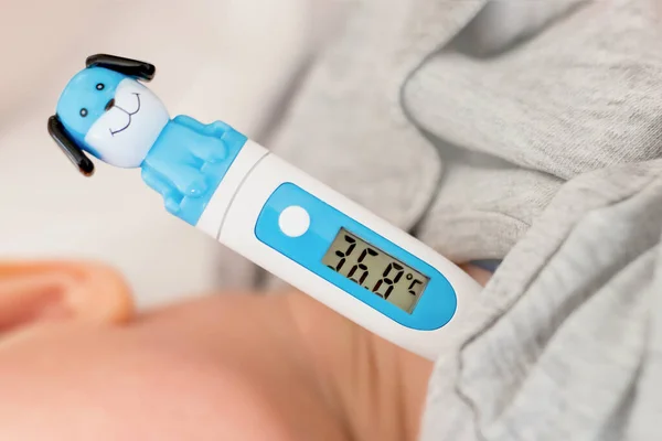 Mom measures the child\'s temperature. Thermometer under the arm. Caring for the health of the baby, prevention of diseases, colds, flu. Normal baby body temperature. Children\'s thermometer design