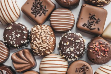 Beyaz arka planda izole edilmiş koyu, beyaz ve sütlü çikolata çeşitleri. Yer mantarı, dekorasyon tasarımlı şeker. Çeşitli şeker dolguları. Yukarıdan görüntüle