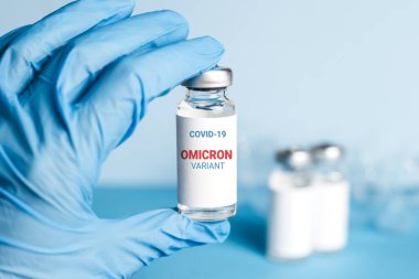 Coronavirus omikron varyant aşısı. Doktorun elinde mavi bir tıbbi eldiven var. İçinde Coronavirus aşısı var. Yeni tür