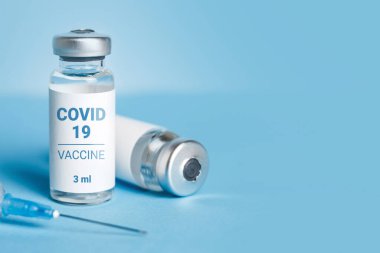 Coronavirus aşısı. Koronavirüs aşısıyla ampuller ve mavi arka planda bir şırınga. Covid-19 tedavisi. Boşluğu kopyala