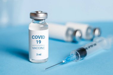 Coronavirus aşısı. Koronavirüs aşısıyla ampuller ve mavi arka planda bir şırınga. Covid-19 tedavisi