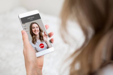 Genç bir kız elinde bir cep telefonu tutuyor ve görüntülü konuşma, video görüşmeleri, konferans...