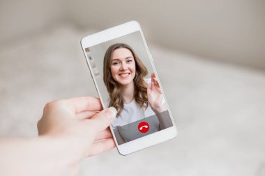 Bir kadın eli ekranda bir kızla cep telefonu tutuyor, görüntülü konuşma. Bir kadın arkadaşına görüntülü arama yapar. Mutlu genç kız telefon ekranında gülümsüyor, arayüz, çağrı düğmeleri