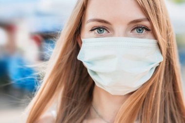 Beyaz bir tıbbi maske takan beyaz bir kızın portresi doğa ve şehir manzarası, koronavirüs, hava kirliliği konsepti