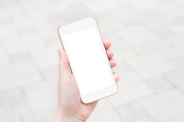Beyaz ekranlı telefon modeli. Beyaz şehrin arka planında beyaz ekranlı beyaz bir akıllı telefonu olan bir kadın el tutuyor. Modelleme. Uzayı kopyala Tasarım için yer